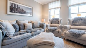 Uma sala de estar com sofá, duas poltronas, uma mesa de centro e um quadro na parede.