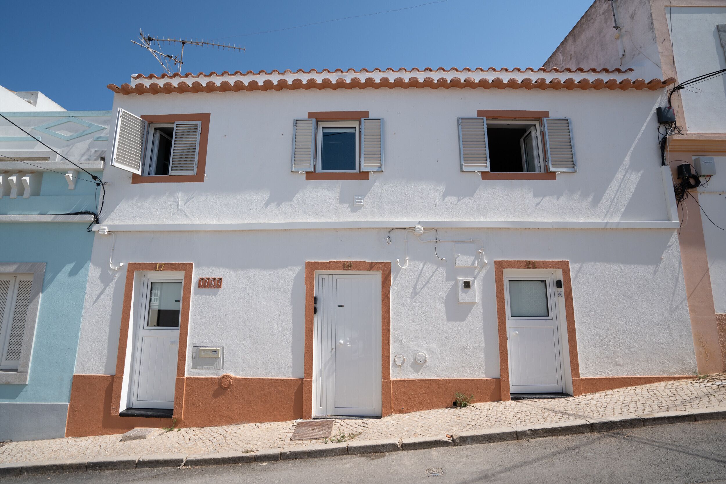 Un bâtiment à deux étages doté de trois portes et de trois fenêtres, chacune équipée de volets.