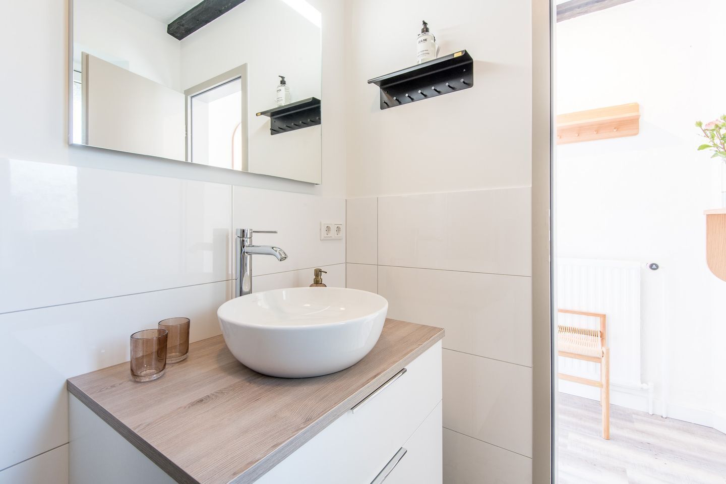 A modern bathroom with a large white sink, a mirror, and a wooden countertop.