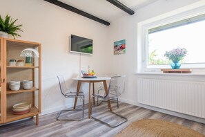 Quarto moderno com mesa de jantar, cadeiras, um armário de madeira e janela com vista.