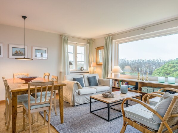 Un salón acogedor con comedor, ventanas amplias y vistas a zonas verdes.