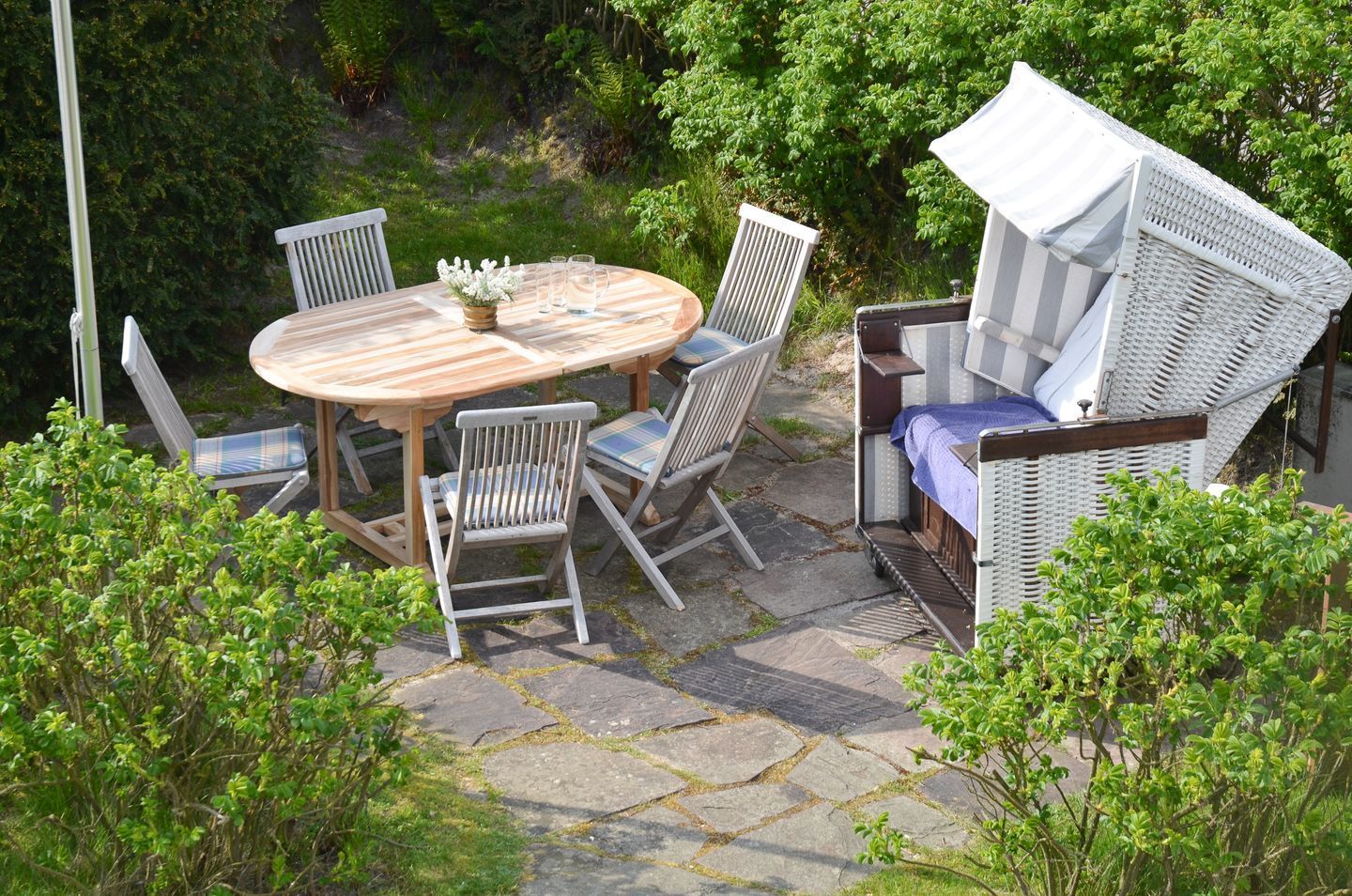 A patio with a round wooden table, four chairs, and a wicker sofa.