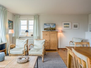 Una habitación acogedora con sillas de mimbre, un armario de madera y una mesa de comedor.