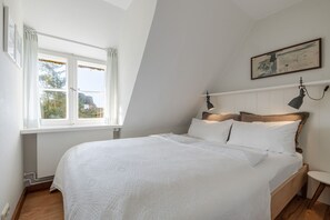 A bedroom with a bed, a window, a painting, and a lamp. - Petit Dünenhof, Germany (Kampen (Sylt))
