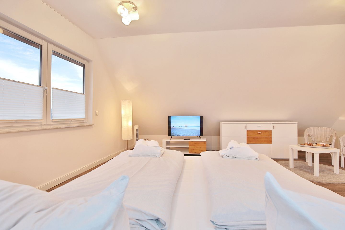 A hotel room with two beds, a TV, a desk, and a chair.