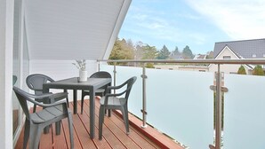 Een overdekt buitengebied met een tafel, stoelen, een plant in pot en uitzicht op een woonwijk.