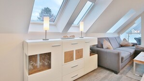 Een moderne loft slaapkamer met dakramen, een grijze bank en een witte kast.