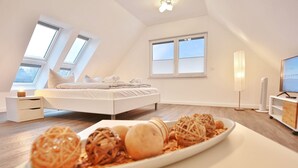 Een moderne slaapkamer met een bed, dakramen, een nachtkastje, een televisie en een dienblad met eten.