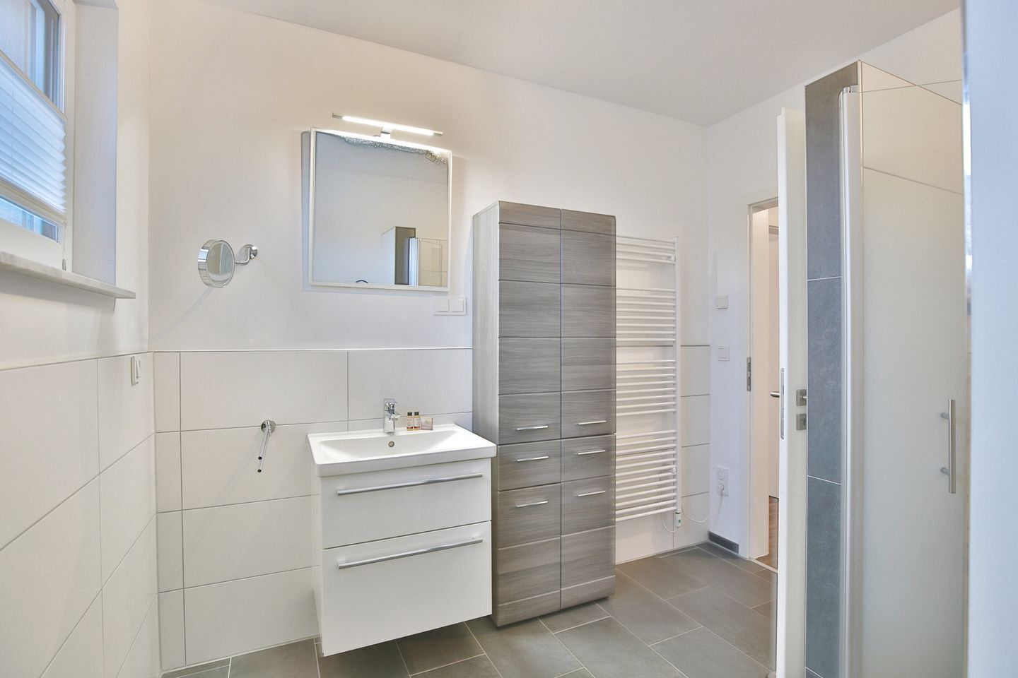 Un baño moderno con lavamanos, espejo y mueble de almacenamiento blanco.