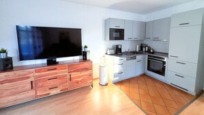 Una cucina moderna con schermo piatto, mobili in legno, forno a microonde e piano cottura.