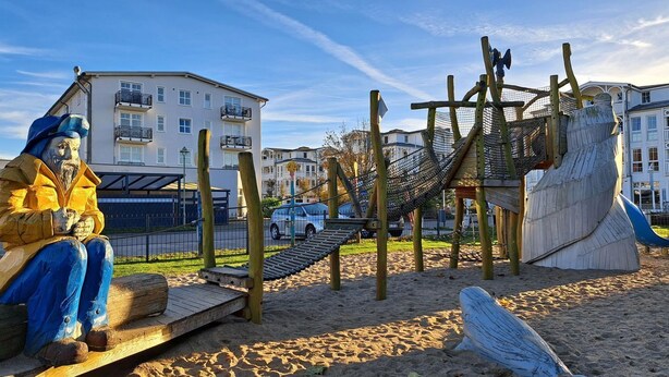 Un parque infantil con estructuras de madera y una estatua.