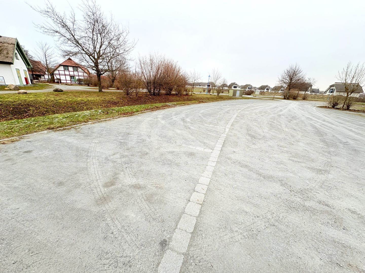 Eine Wohnstraße mit Häusern, einer gepflasterten Straße und kahl stehenden Bäumen.