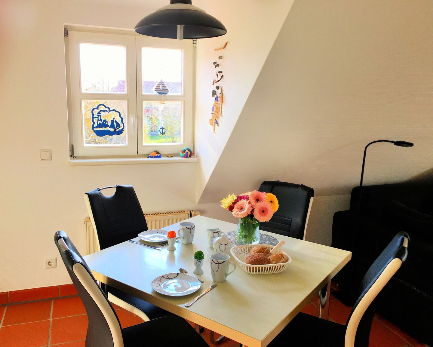 A dining area with a table set for two, a window with artwork, and a radiator.