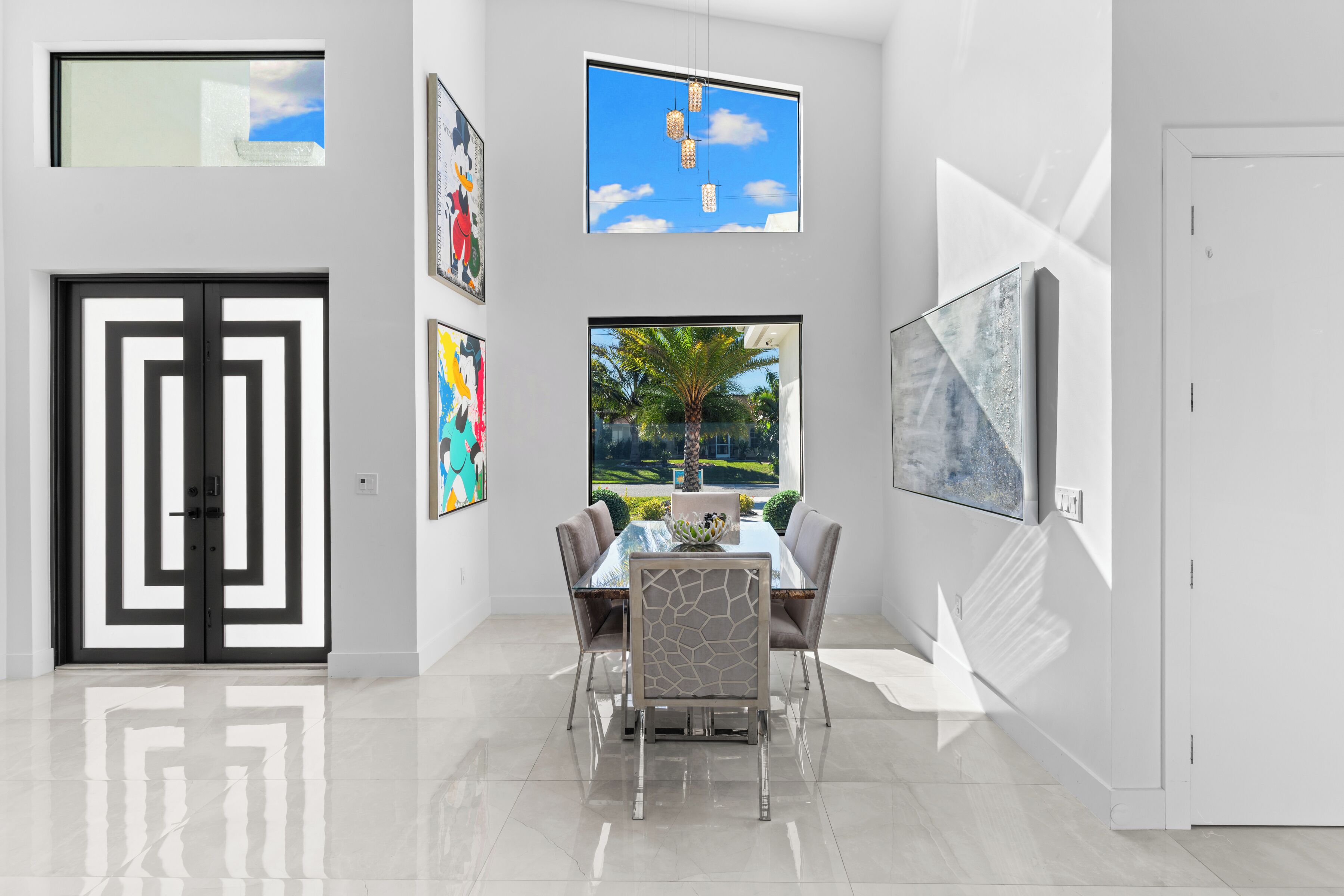 A modern dining area with a glass table, chairs, and artwork on the walls.