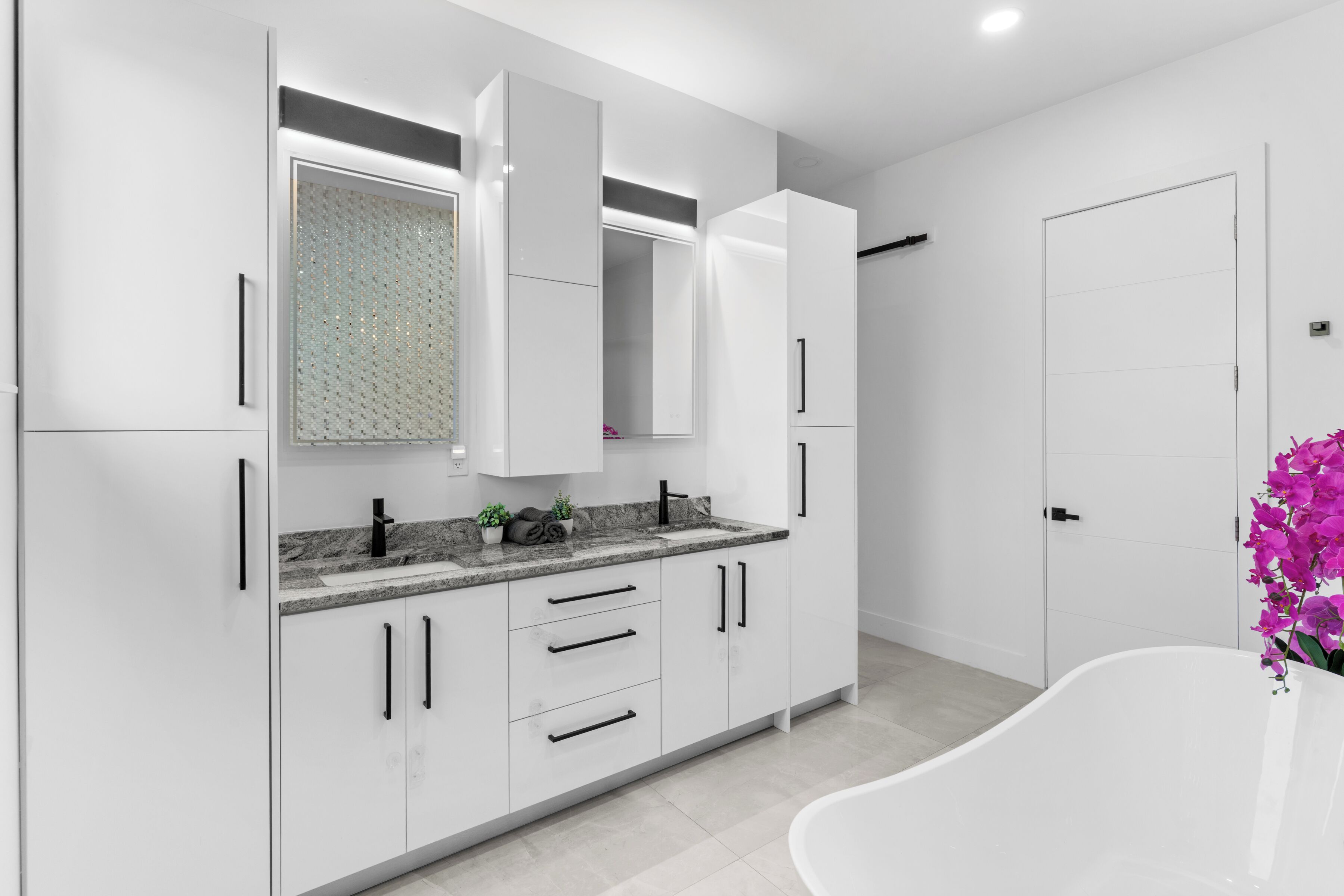 A modern kitchen with white cabinets, a granite countertop, and a built-in oven.
