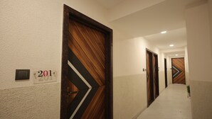 Un pasillo con puertas de madera, una pared con textura y un cartel que indica la habitación 201.