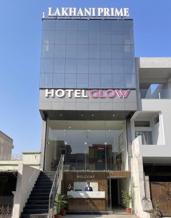 A modern hotel building with a reception desk and a staircase leading to the entrance.