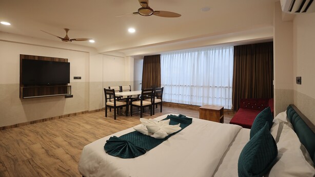 Una habitación de hotel con una cama, un escritorio, un televisor y un ventilador de techo.
