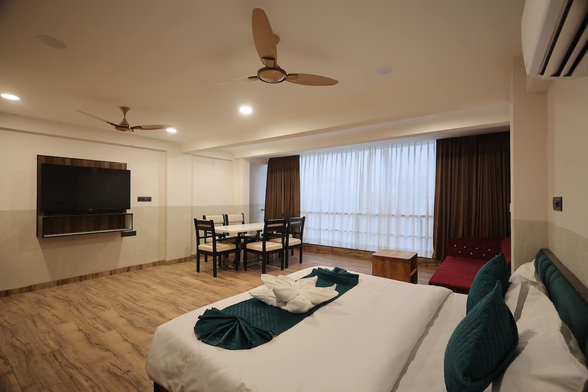 Una habitación de hotel con una cama, un escritorio, un televisor y un ventilador de techo.
