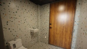 Un baño con inodoro, lavabo y puerta de madera.