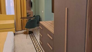 A hotel room with a bed, a desk, a chair, a mirror, and an air conditioning unit. - Delightful beachfront apartment equipped with all the comforts (Lido di Ostia)