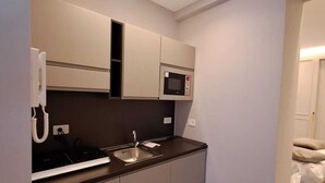 A compact kitchenette with a microwave, sink, and built-in oven. - Delightful beachfront apartment equipped with all the comforts (Lido di Ostia)