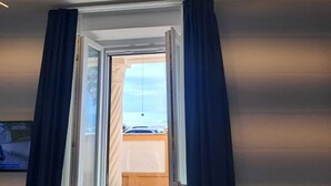 A room with a large window, a bed, and a ceiling light. - Delightful beachfront apartment equipped with all the comforts (Lido di Ostia)