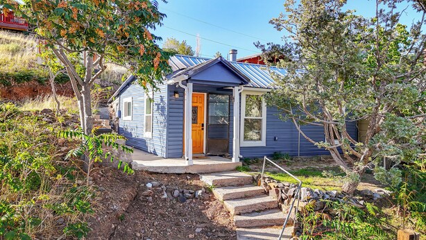 A small, single-story house with a porch and a chimney. - Historic Pioche Retreat | Near Trails & Cathedral Gorge (Pioche)