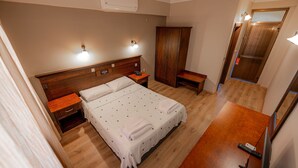 A neatly arranged bedroom with a large bed, bedside tables, a wardrobe, and a bench. - Golmar Beach& Spa Hotel (Marmaris)