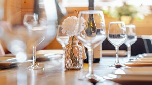 A dining table with wine glasses, a bottle, and a vase with flowers. - Hameau des clos Virolet (Les Gets)