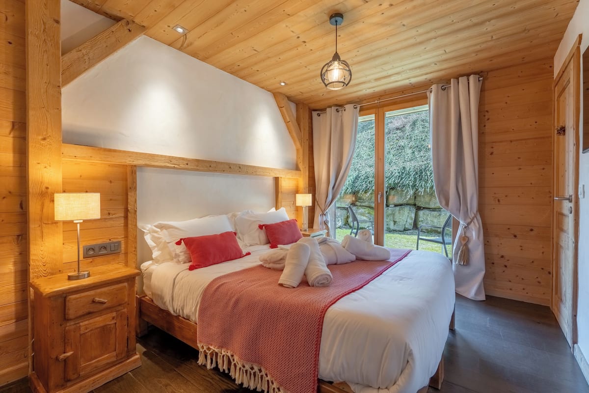 A wooden cabin-style bedroom with a bed, nightstands, and a window with curtains.