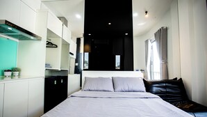 Een moderne slaapkamer met een groot bed, zwart-wit inrichting, een inbouwkleerkast en een raam met gordijnen.