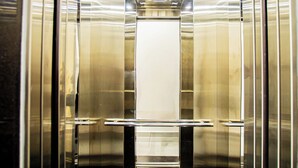 Een liftinterieur met glanzende metalen wanden en een centraal lichtarmatuur.
