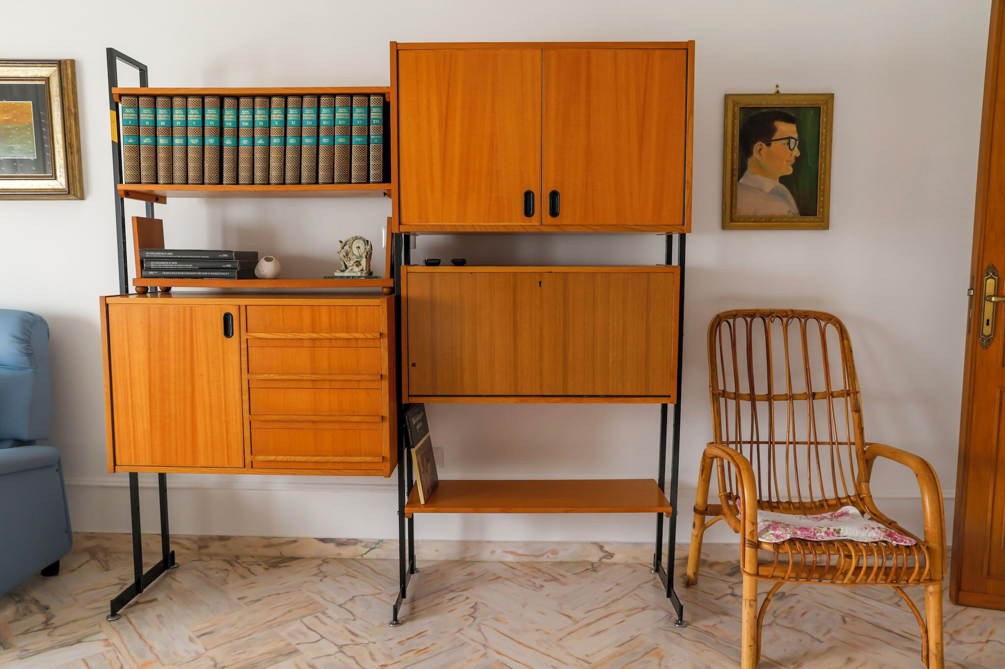 A room with a wooden cabinet, a wicker chair, and a bookshelf.