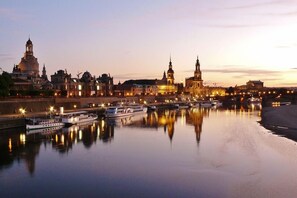 A river with boats docked, a bridge, and historic buildings along the riverbank.