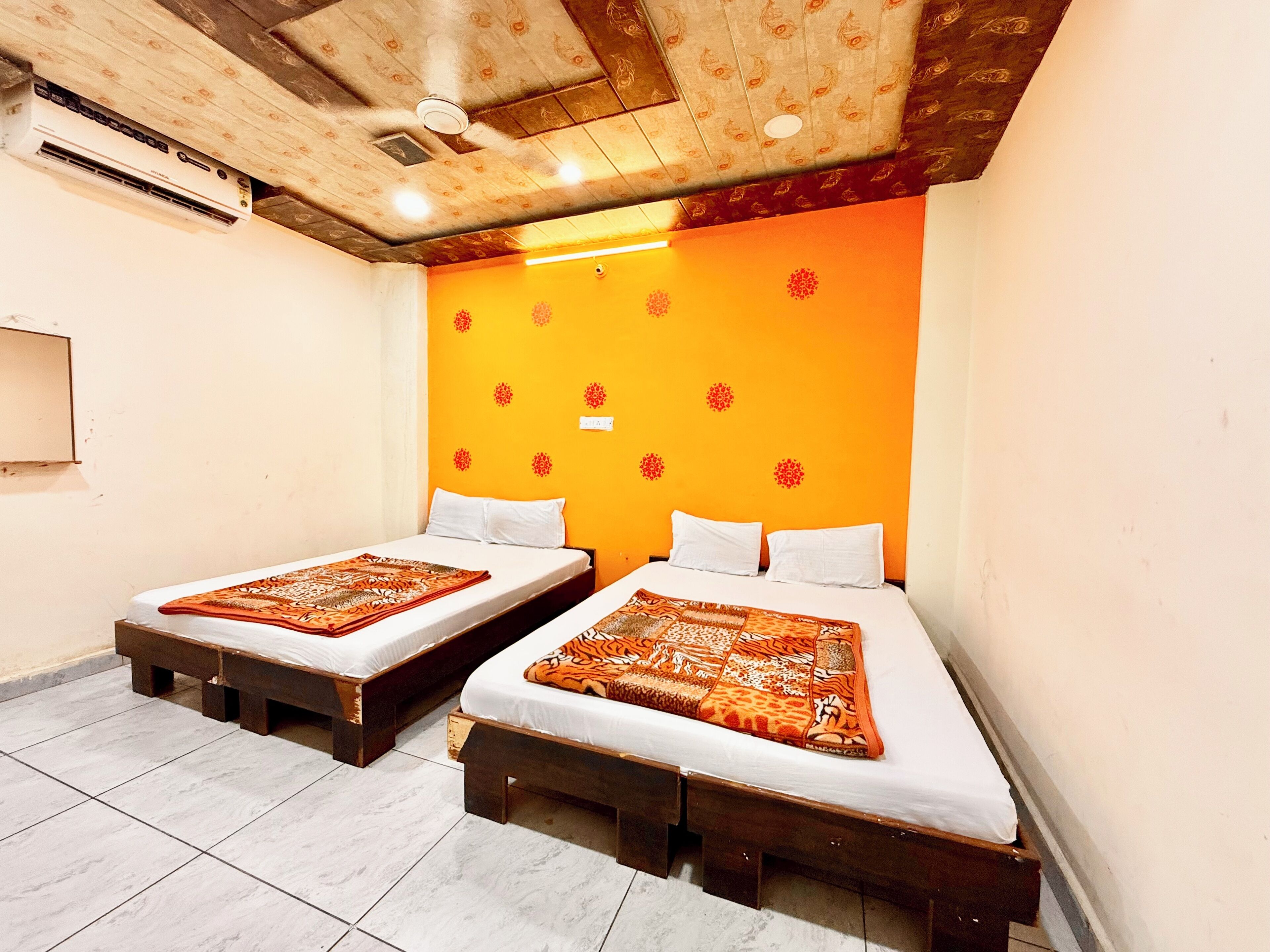 A room with two beds, wooden headboards, a ceiling with a wooden pattern, and a wall with a floral design.
