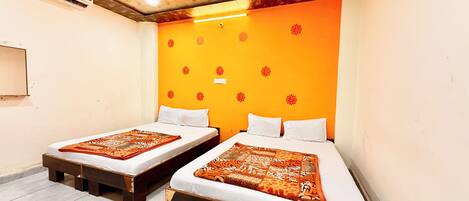 A room with two beds, wooden headboards, a ceiling with a wooden pattern, and a wall with a floral design.