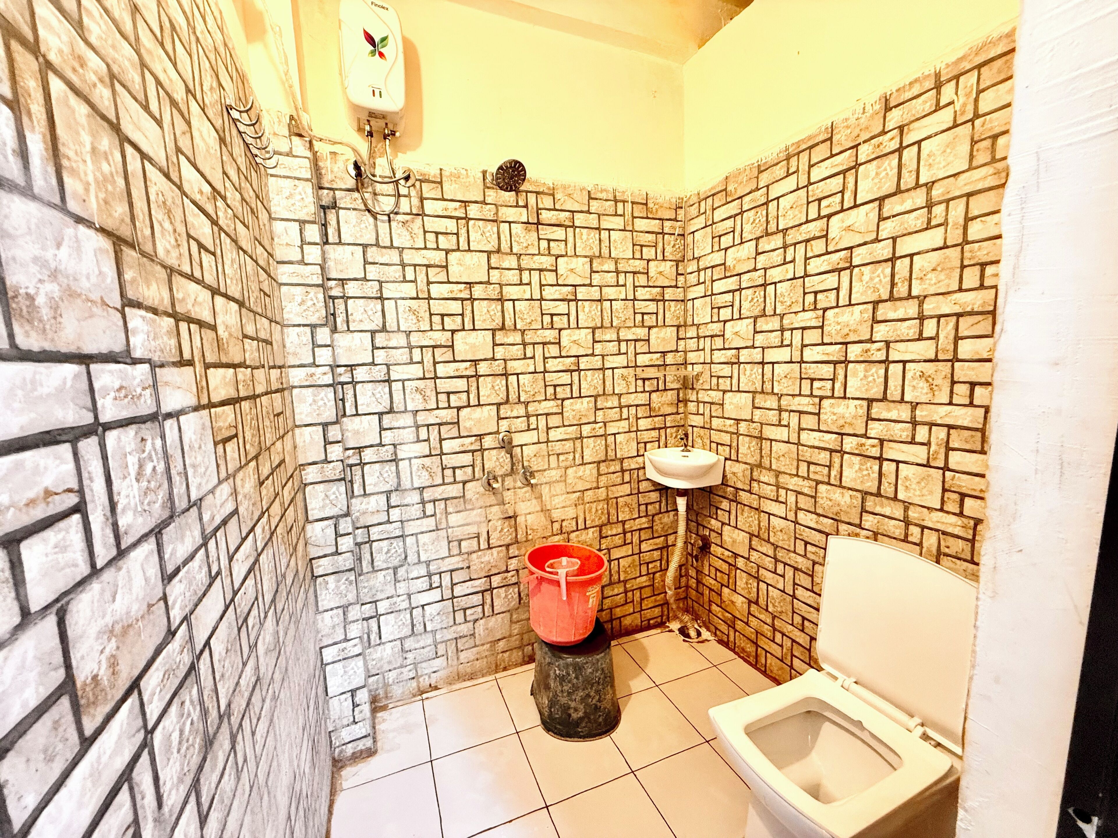 Un baño con pared de ladrillo, inodoro y lavamanos.