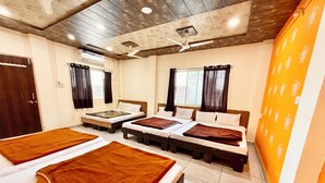 Een hotelkamer met drie bedden, een houten plafond en een raam met gordijnen.