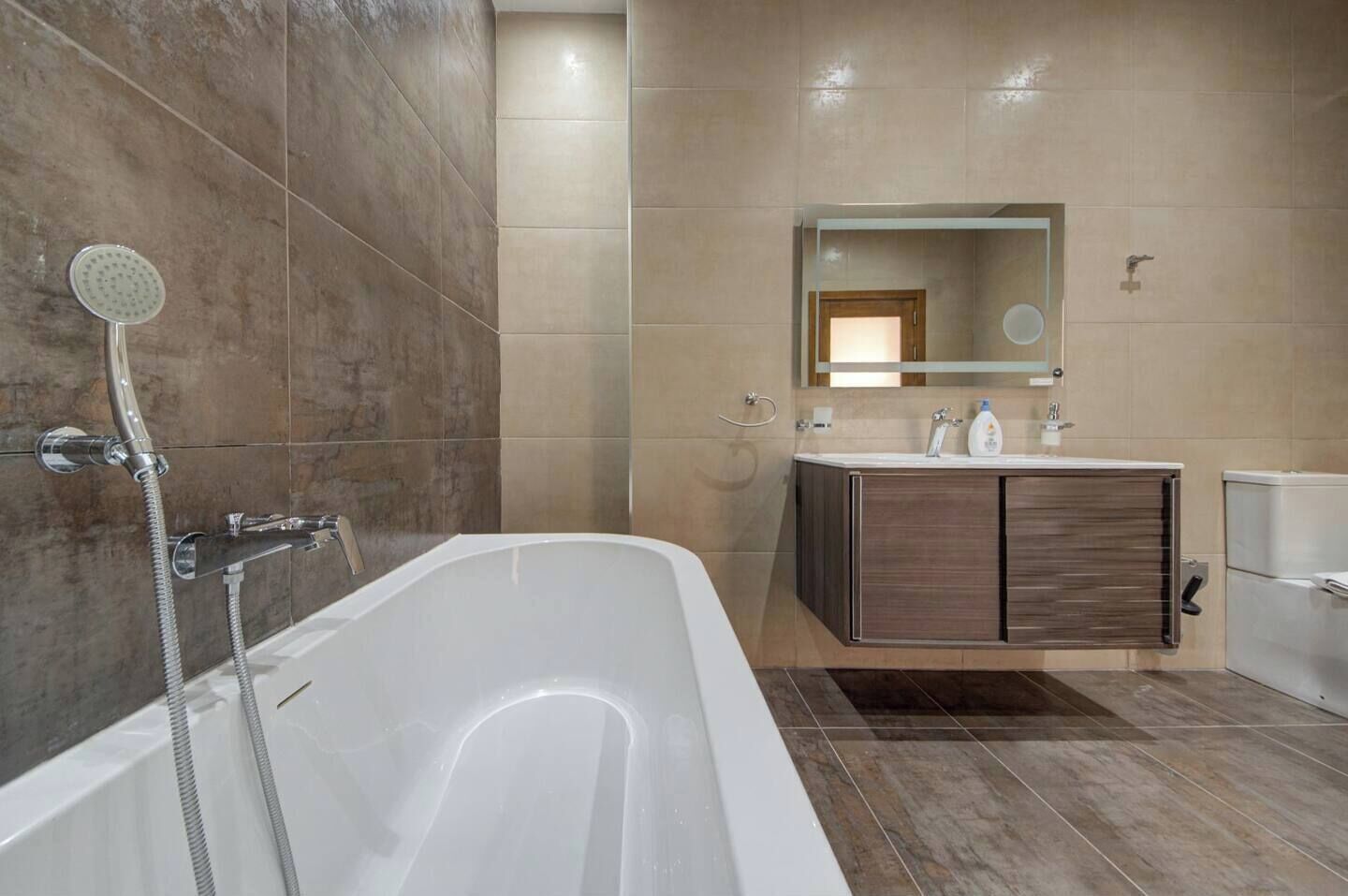 A modern bathroom with a freestanding bathtub, a vanity with a mirror, and a showerhead.