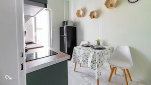 Una cocina moderna con comedor, un refrigerador y un reloj en la pared.