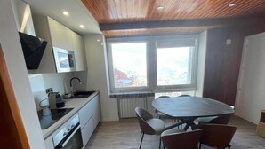 Eine moderne Küche mit Essbereich, großen Fenstern und einer Holzbalkendecke.