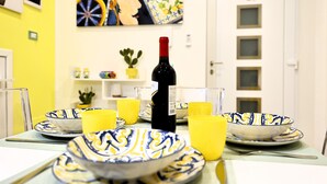 A dining table with yellow and blue patterned bowls, a bottle of wine, and yellow glasses. - SIKELIA HOUSE - COMFORT APARTMENT Hospitality and elegance in the heart of Palermo (Palermo)