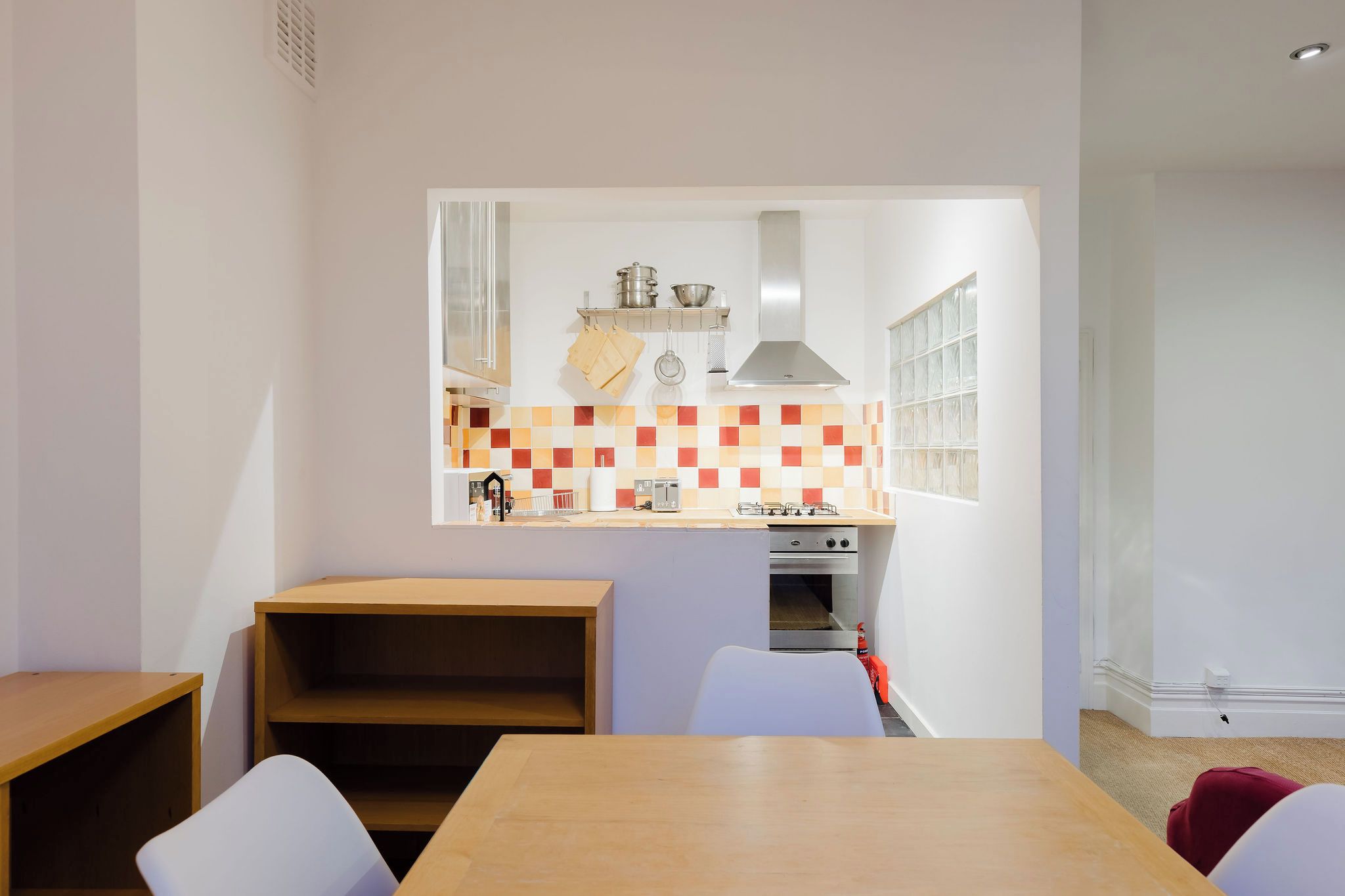 A compact kitchen with a modern design, featuring a built-in oven and a window above the sink.
