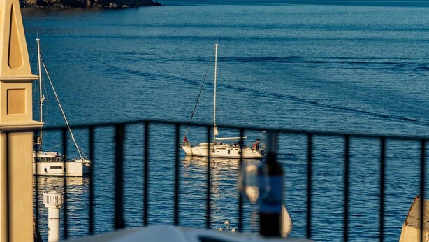A seaside view with a railing, a boat, and a building on the left. - Pietra Menalda - Apartment with sea-view terrace (Lipari)