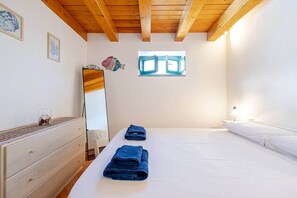 Ein Schlafzimmer mit Bett, Schminktisch, Spiegel und Fenster.