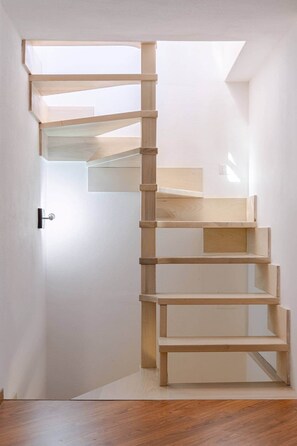 Eine Holztreppe mit minimalistischem Design, die zu einer höheren Etage führt.