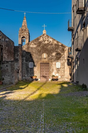 A historic church with a bell tower, cobblestone path, and a small garden area.