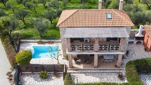 A two-story building with a tiled roof, a swimming pool, and outdoor seating. - Valory s Stone House (Zakynthos)