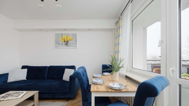 Ein modernes Wohnzimmer mit einem dunkelblauen Sofa, einem Holzessttisch und einem blauen Sessel.